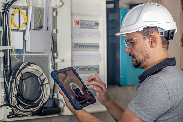 Praetorian Solutions website image of network engineer wearing a white hard hat whilst testing network speed on tablet. Praetorian Solutions install Ubiquity network components.
